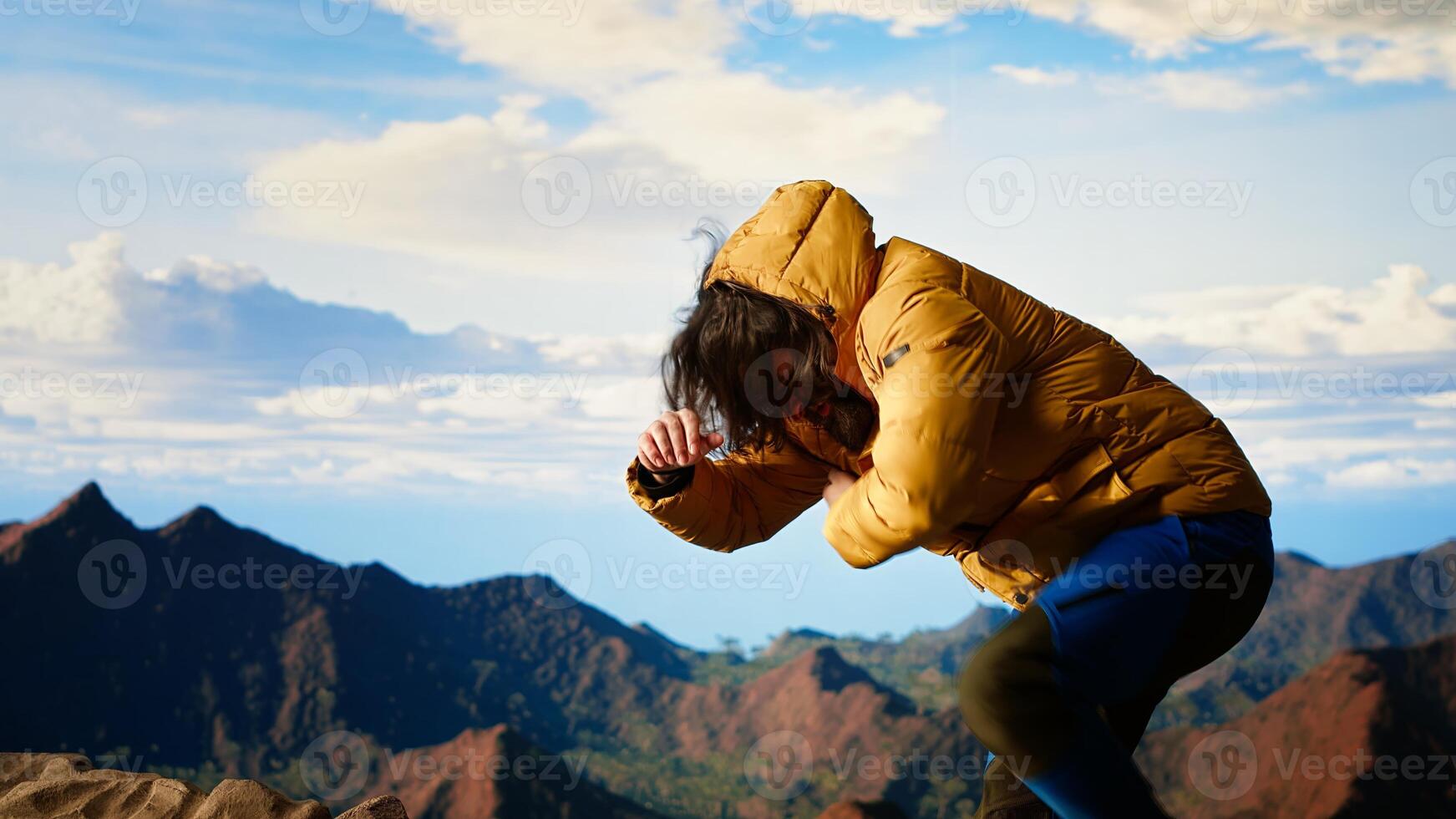 Clumsy traveler loses balance on steep mountain peak as powerful winds knock him off course, falling and being unequipped in expedition. Hiker unprepared for cold weather. Camera B. photo