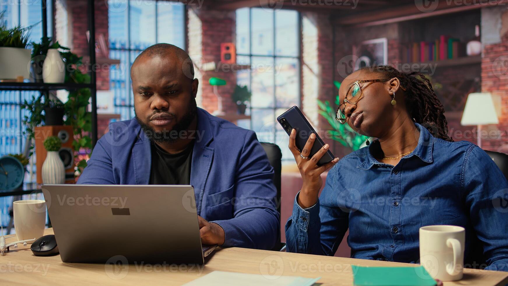 African american people spending time together at home with different activities, young man working and earning money while girlfriend uses smartphone, scrolling on websites. Camera A. photo