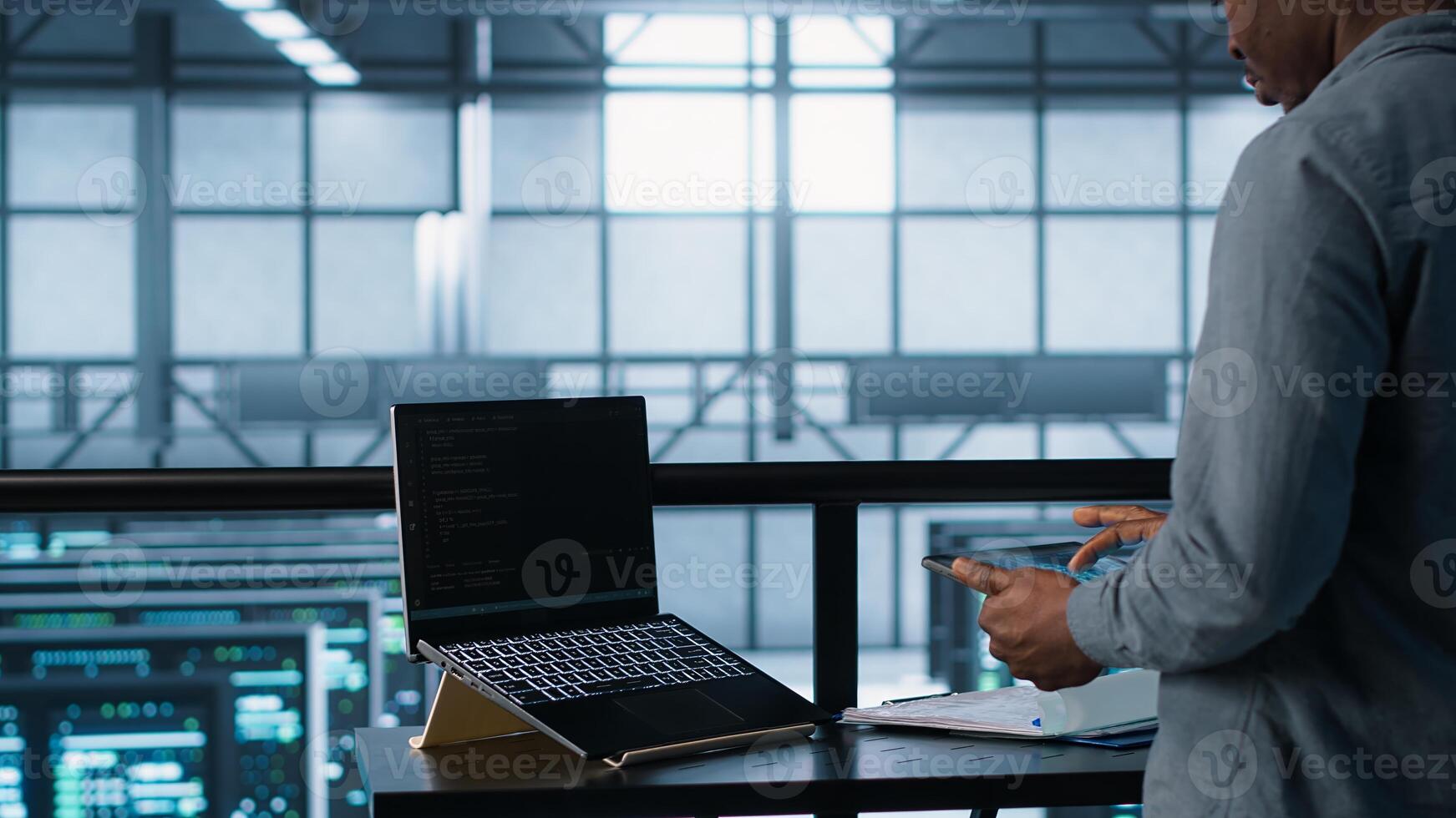 Admin using artificial intelligence tech on tablet and laptop. Man in server farm using AI on devices to update storage arrays, improving performance, camera A photo