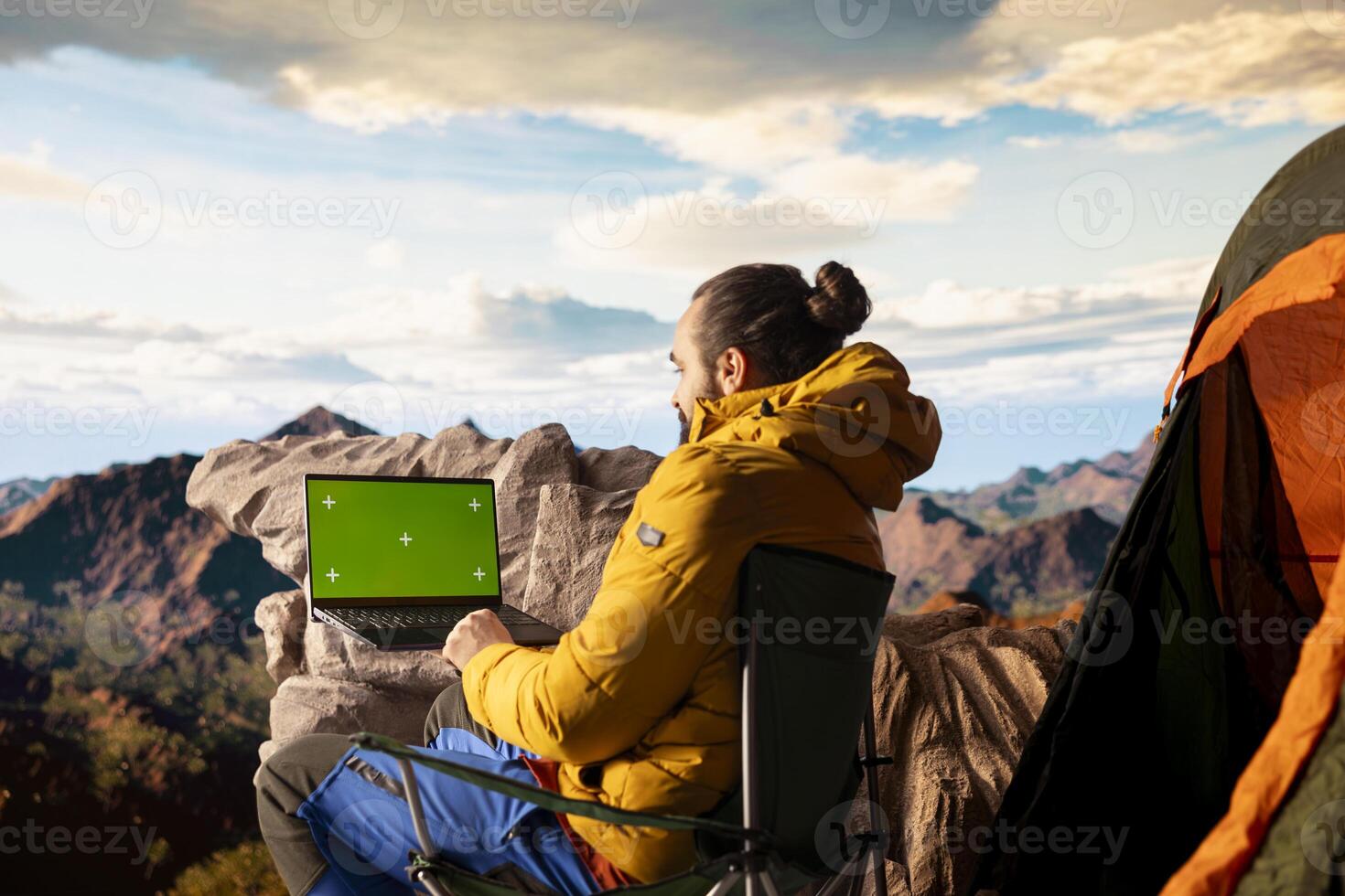 Adventure seeker stands at mountain peak next to isolated chroma key, looking out at scenic view that stretches endlessly. Fresh air and breathtaking landscape. photo