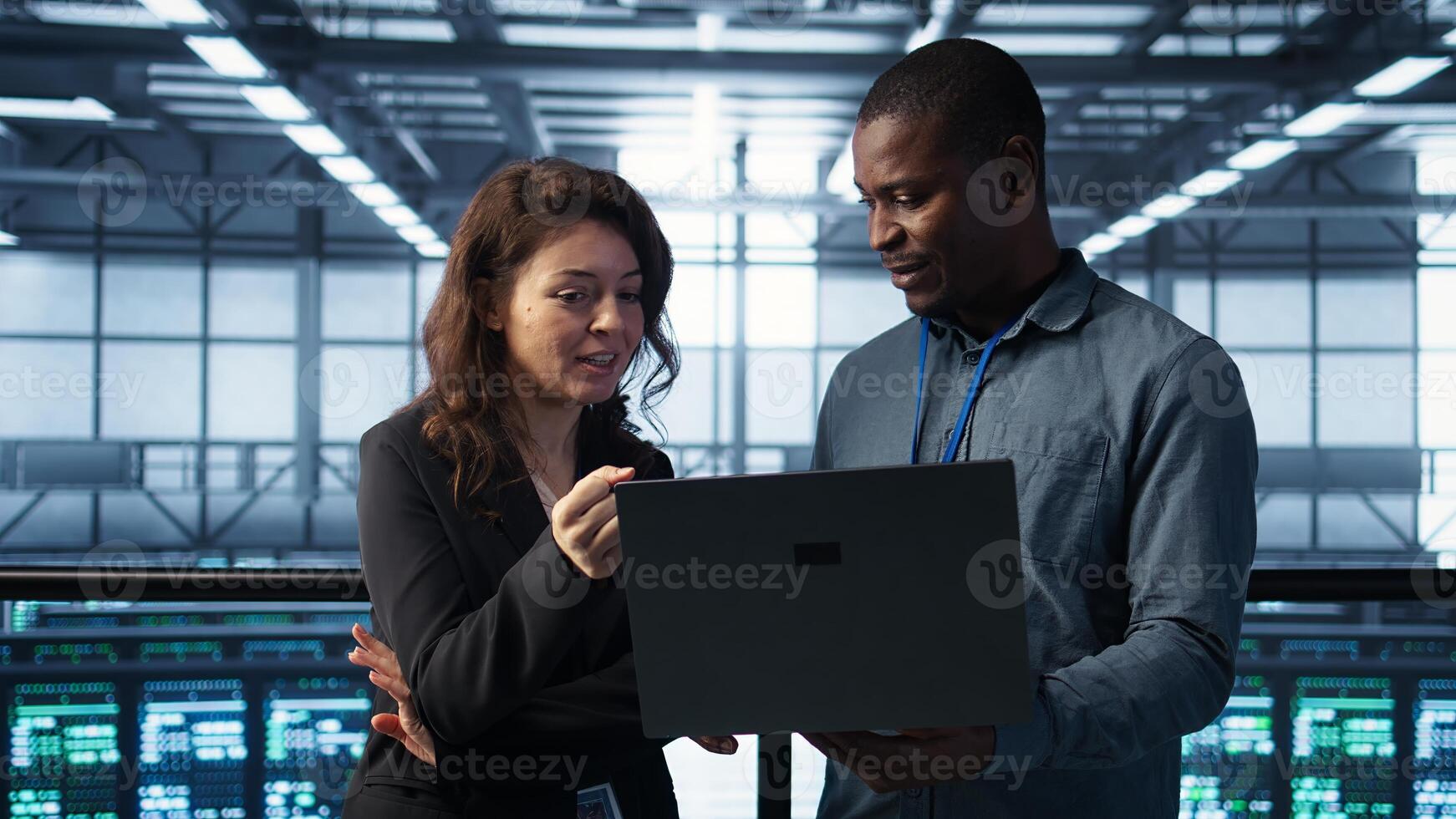 Engineers using laptop, managing server virtualization, running scripts. IT specialists using programming language on notebook in server hub, finetuning network protocols, camera B photo