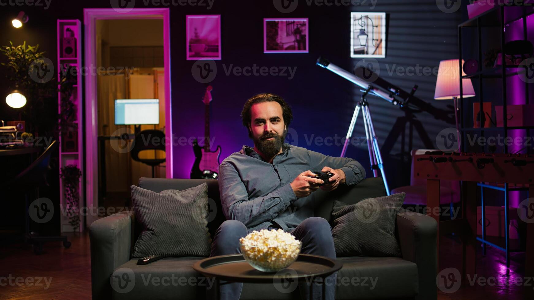Gamer sitting on couch engaging in online competitive multiplayer game using controller. Upbeat player engaging in fun videogames, enjoying leisure time, camera B photo