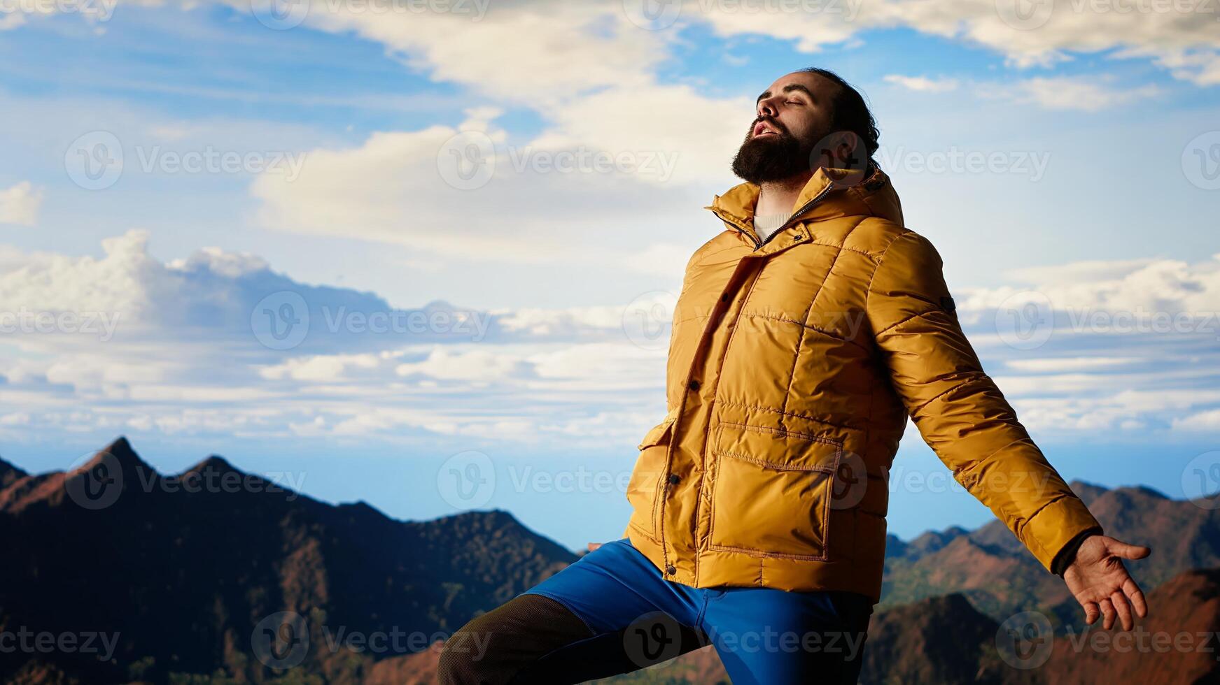 Peaceful traveler feeling happy after climbing mountain, enjoying mindfulness and determination. Young man being passionate about wilderness and scenic view. Camera B. photo