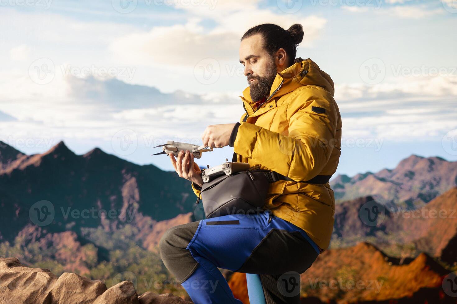 Modern traveler creating content and filming with drone, climbing on top of high altitude mountain range. Hiker enjoying landscape scenery, remote control. photo