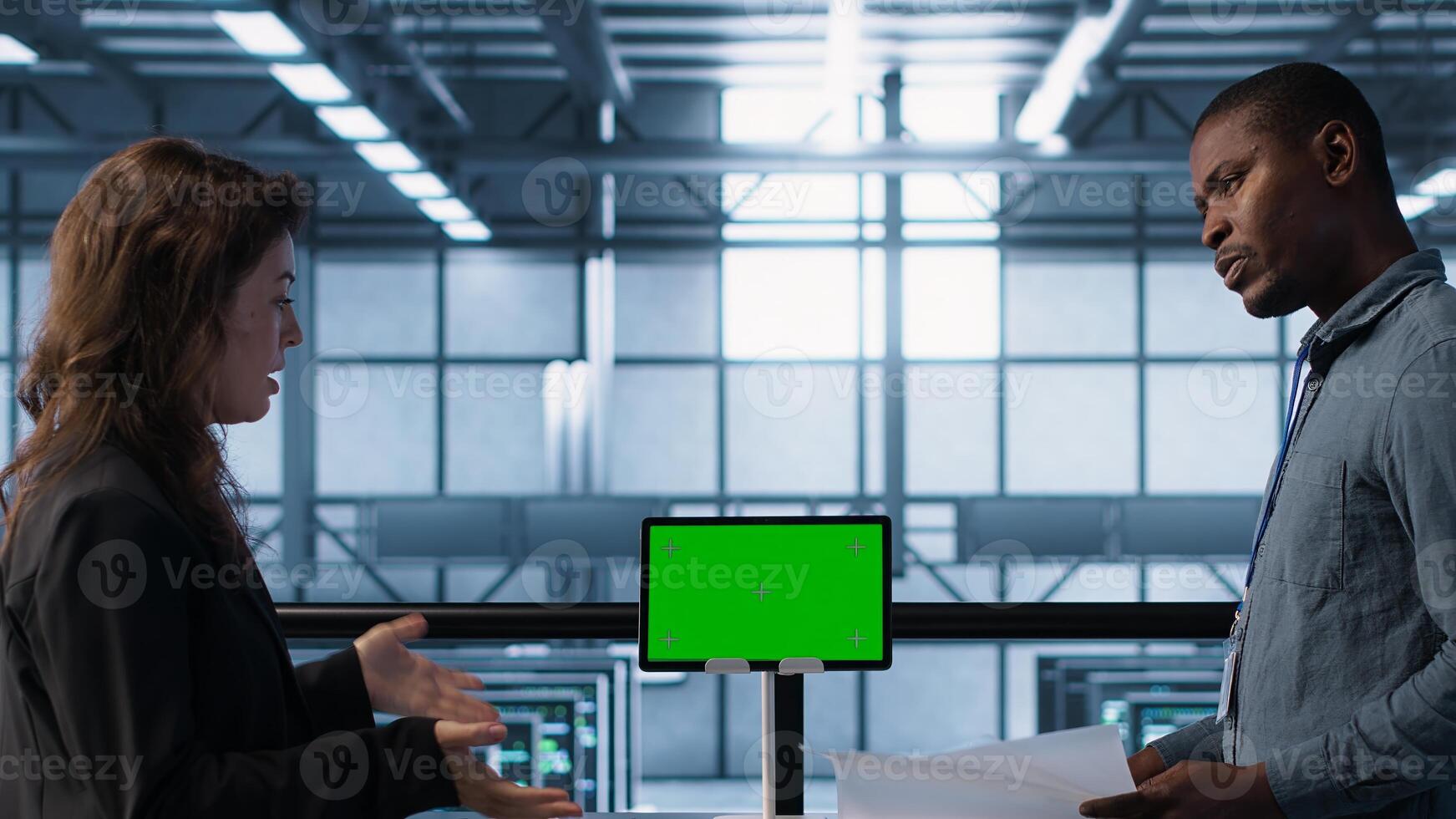Engineers overseeing server room with mockup device, reading hardware documentation. Team doing inspection in data center hub, reading technical files on green screen tablet, camera A photo