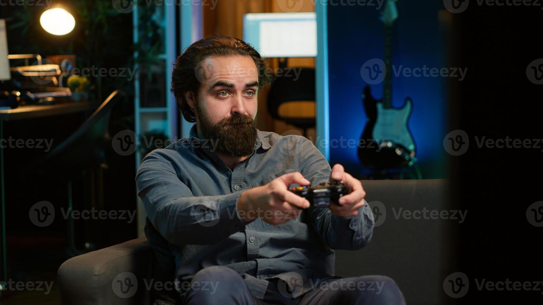 Man playing videogame in neon lit room, holding controller. Gamer participating in internet esports competition using professional gamepad for better victory chances, camera A photo