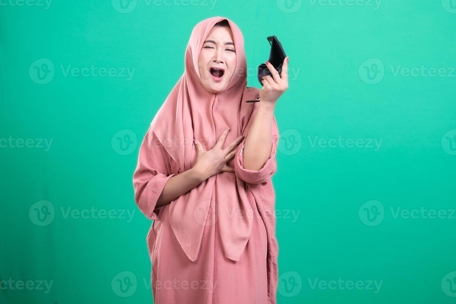 Distressed muslim woman with broken phone expressing shock and d photo