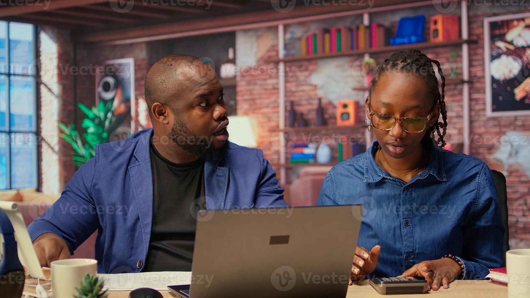 African American couple discussing mortgage and insurance payments at home, using calculator to do household budgeting and money management. Ensuring secure financial future. Camera A. photo