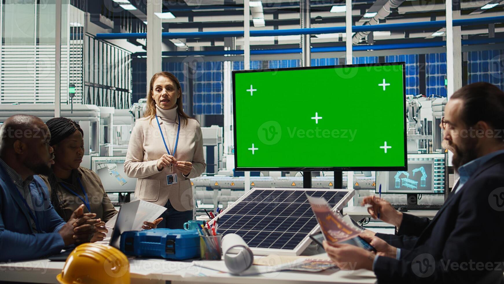 Engineers look over assembly lines schematics during business meeting in front of green screen monitor. Experts work on industrial plant configurations using mockup display, camera A photo
