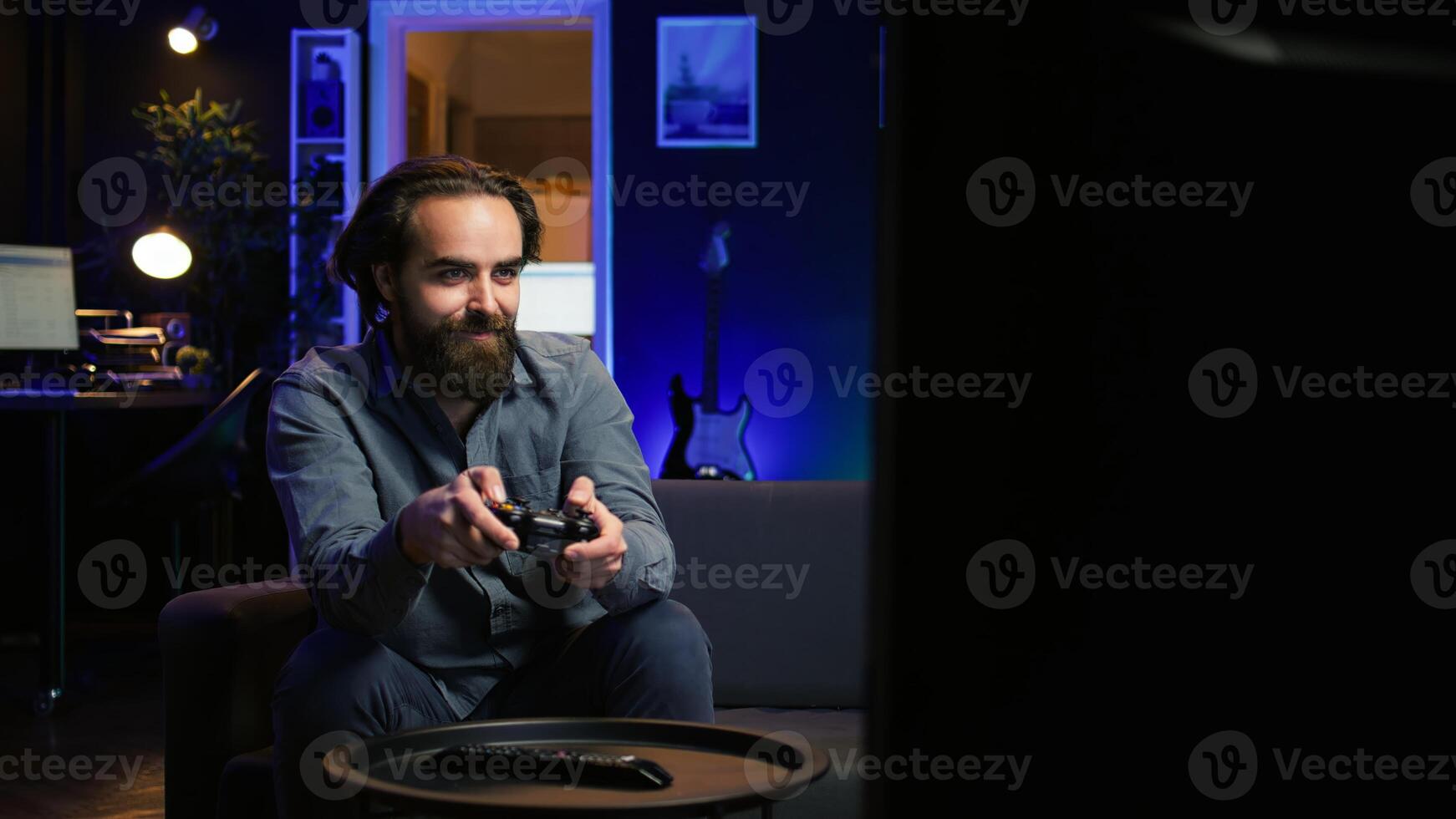 Happy person arriving home, excited to do gaming during leisure time. Cheerful player entering room, jumping on couch, excited to play videogame on console, relaxing after work photo