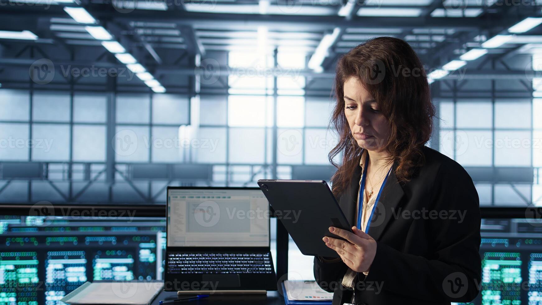 Admin in data center using AI tech on tablet to deploy new server architectures. Woman in server room updating storage arrays to maintain stable performance, camera B photo