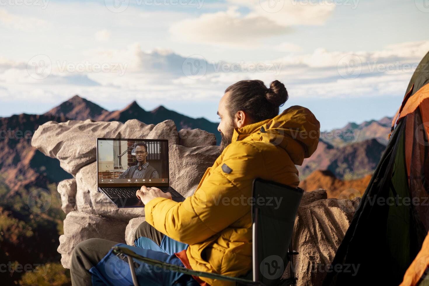 Workaholic explorer meeting with colleagues on online call, enjoying strong signal high speed internet on top of mountain. Young hiker entrepreneur with work dependency. photo