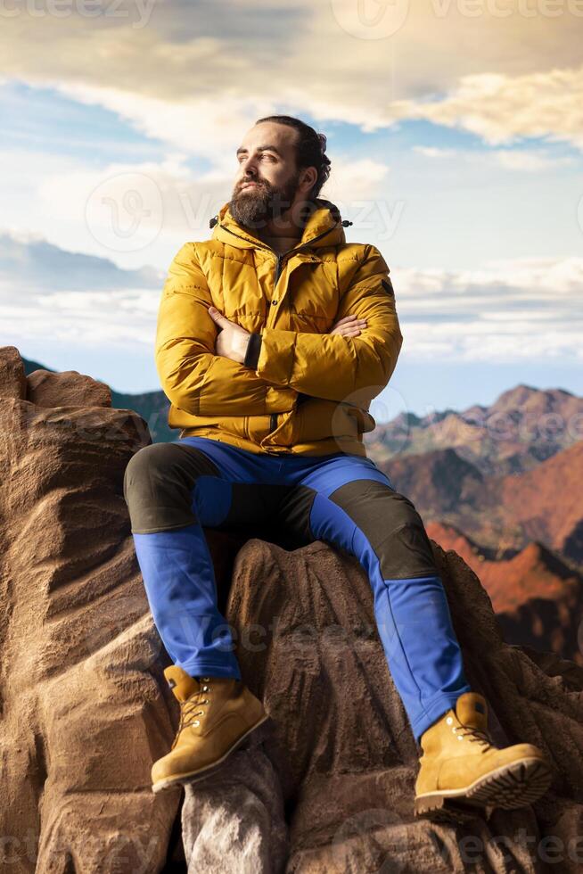 Explorer on mountain top taking in fresh air and panoramic scenery. Climber nature lover admires stunning landscape of rugged peaks and vast sky, adventure and sightseeing. photo