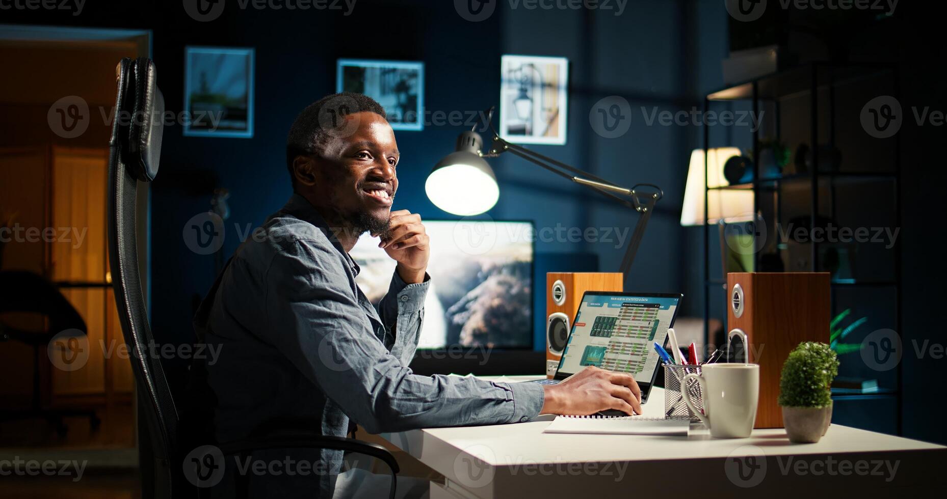Black young adult working remotely and organizing information, reviewing notes and making data driven decisions to complete freelancing tasks. Managing schedule efficiently. Camera A. photo
