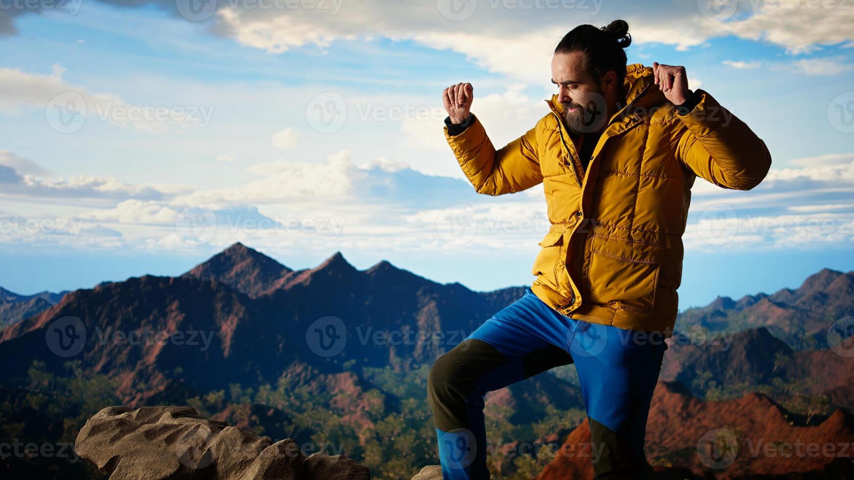 Happy climber cheering and feeling pleased while he stretches arms toward the sky, feeling the satisfaction of a personal achievement and victory. Stunning panoramic view. Camera A. photo