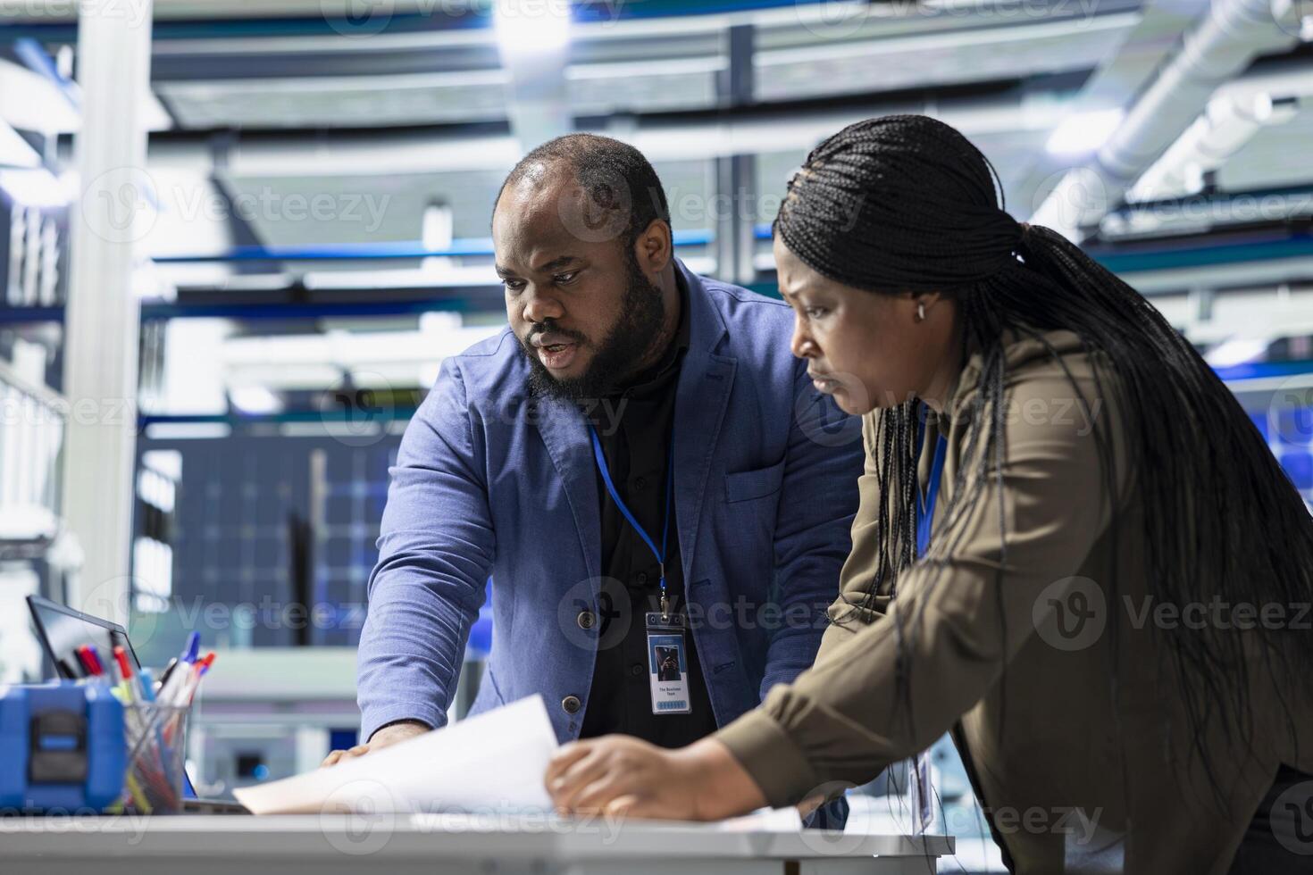 Black team of engineers technicians share ideas in a solar panel factory, reviewing blueprints and sharing ideas to enhance renewable energy production and sustainable innovation. photo