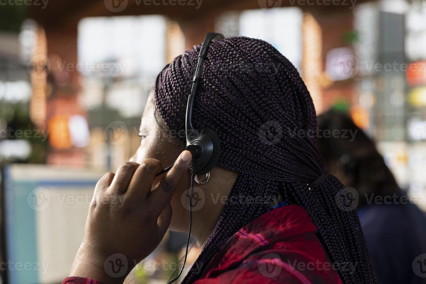 Call center agent in office using headset mic to answer customers questions, close up. Woman in customer support workspace in front of PC using audio headphones microphone to talk with clients photo