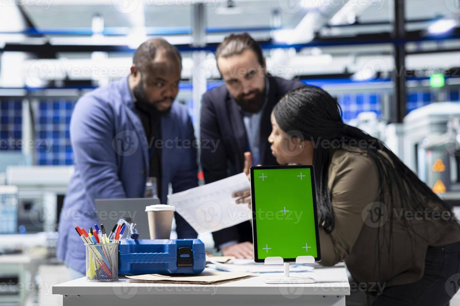 Solar panel diverse group reviewing insight on pc next to green screen, finding errors during a process audit and helping optimize renewable energy operations. Photovoltaics factory. photo