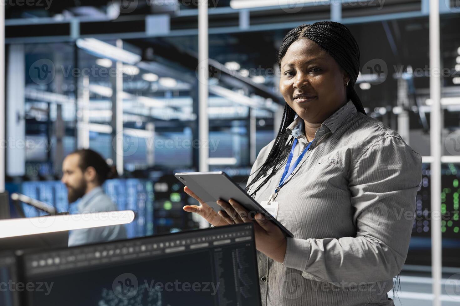 Portrait of smiling data center programmer using tablet to update servers tech, configuring gear using software tools. Happy server farm worker reviewing hardware analytics using device photo