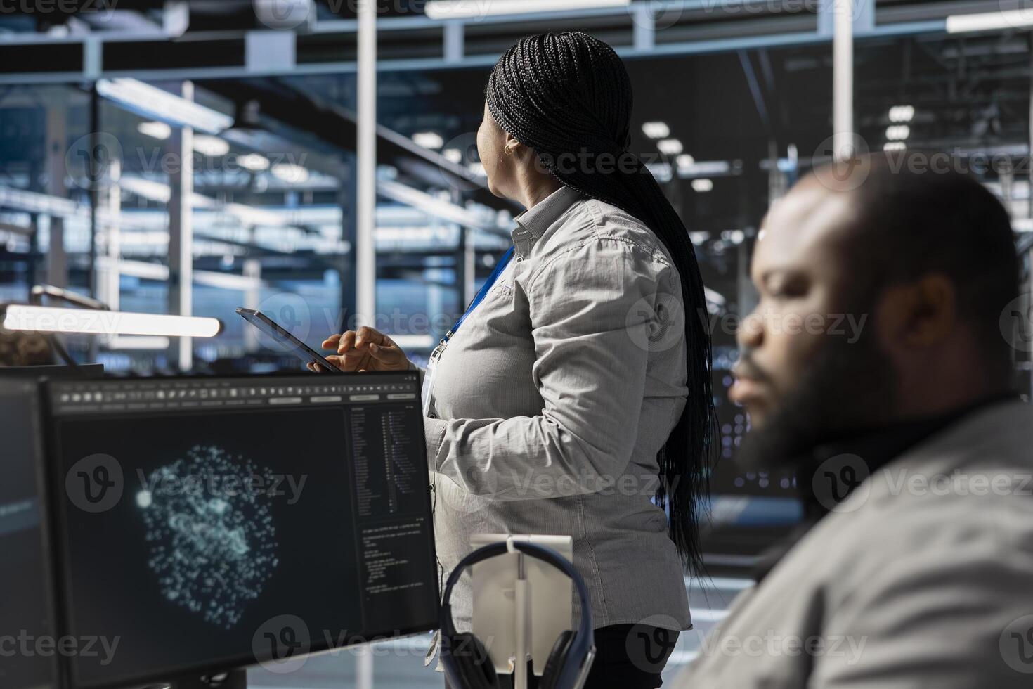 Data center employee monitoring system performance using PC, identifying malfunctions. African american server farm IT expert troubleshooting computer bugs, implementing optimizations photo