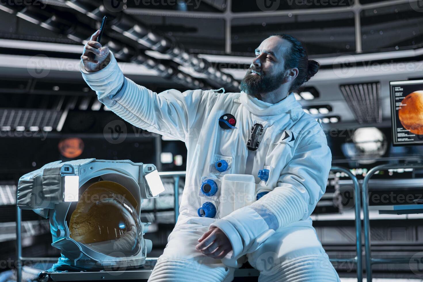 Smiling cosmonaut takes selfie inside space station with Mars mission screen glowing in background. Happy spaceship crew member doing photos using phone before landing on red planet