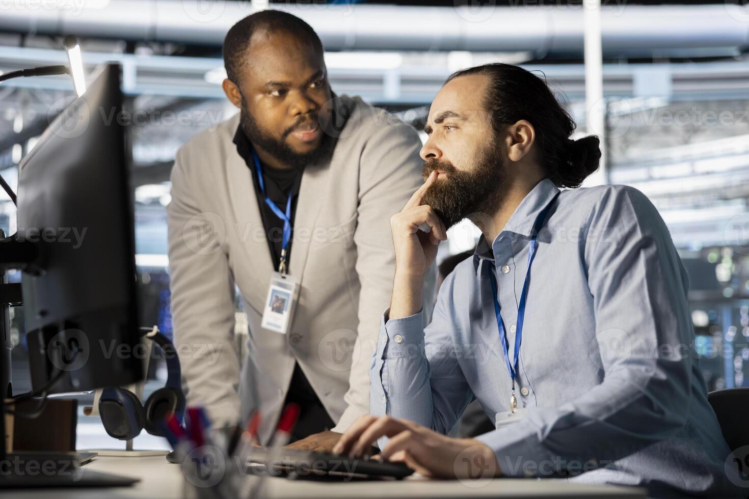 Data center manager supervising work done by employee verifying neural network parameters. Server hub supervisor overseeing worker inspecting configurations to ensure optimal performance photo
