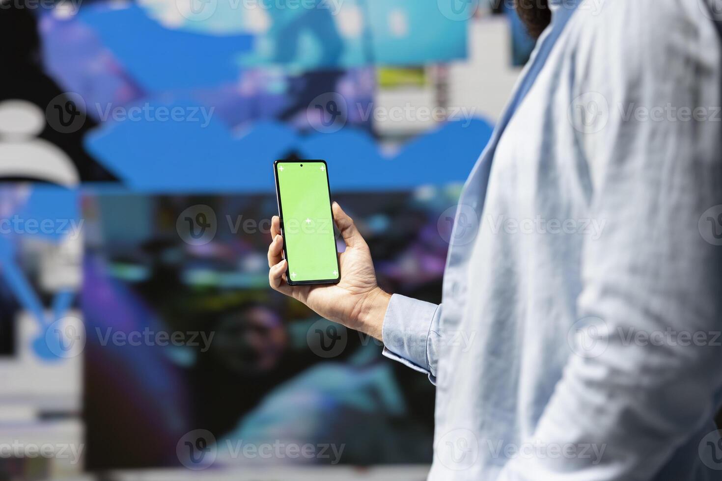 Male influencer holds phone with chroma key screen for online presence, using his imagination and storytelling skills to connect with followers and boost online engagement. Modern web design. photo
