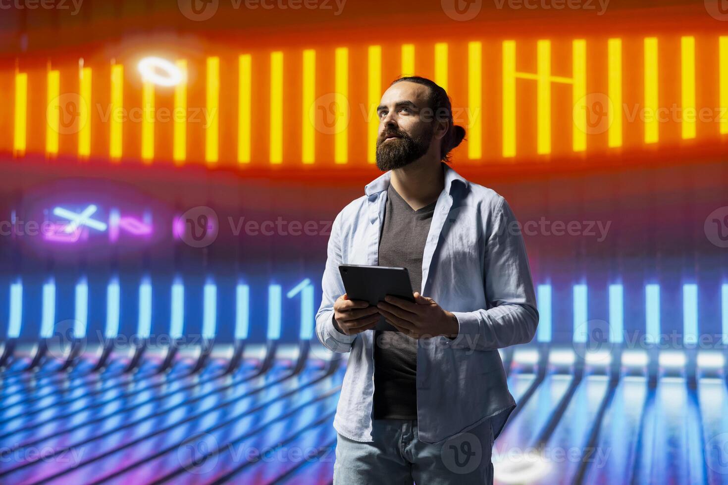 Cool young man standing beneath glowing neon lights surrounded by vibrant colors and a futuristic atmosphere. Express individuality, urban style and creative attitude in a nightlife scene. photo