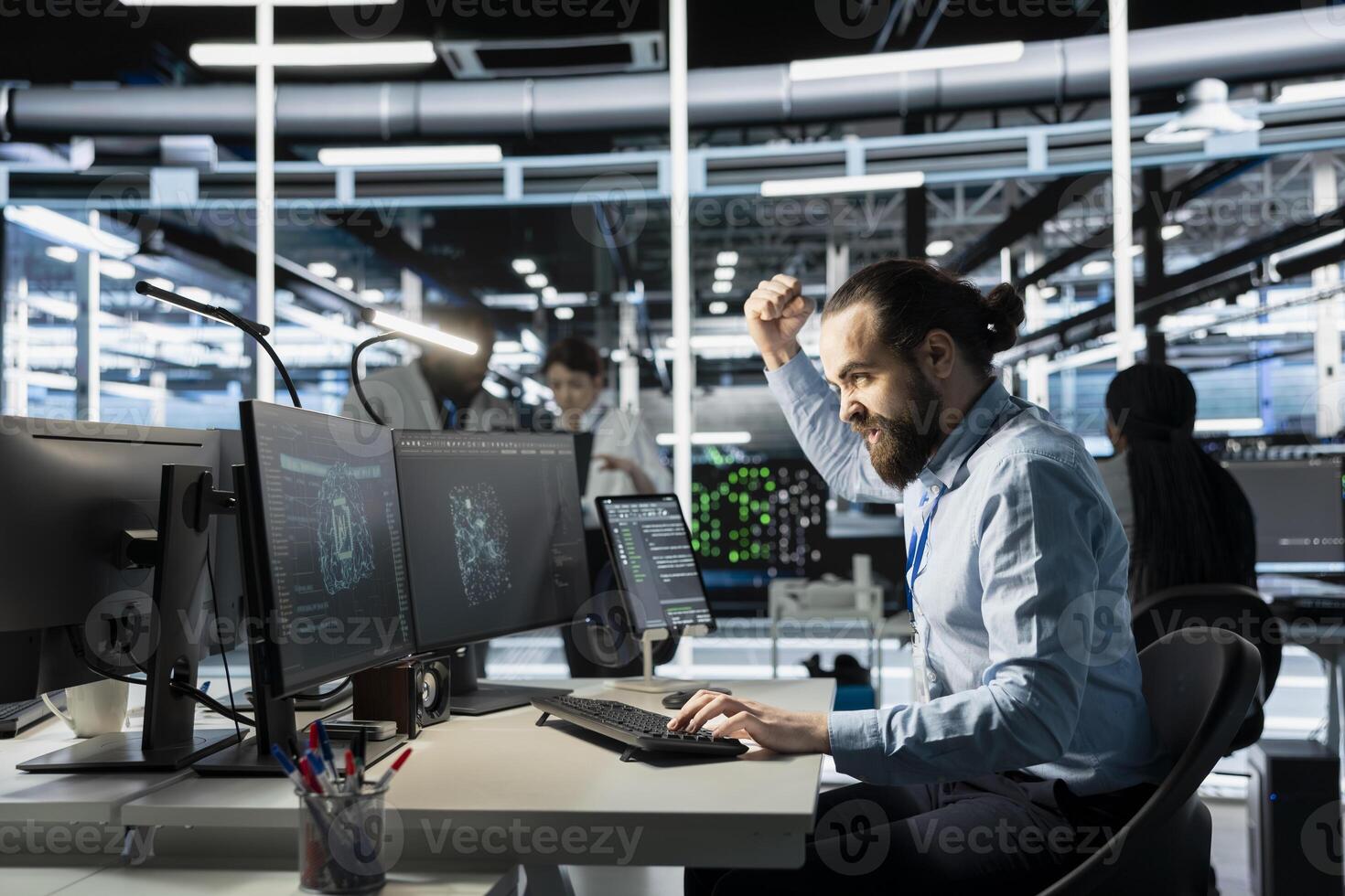 Angry software developer in data center clenching fists while looking at AI visualization interface on monitor. Frustrated technician reacting to artificial intelligence software glitches photo