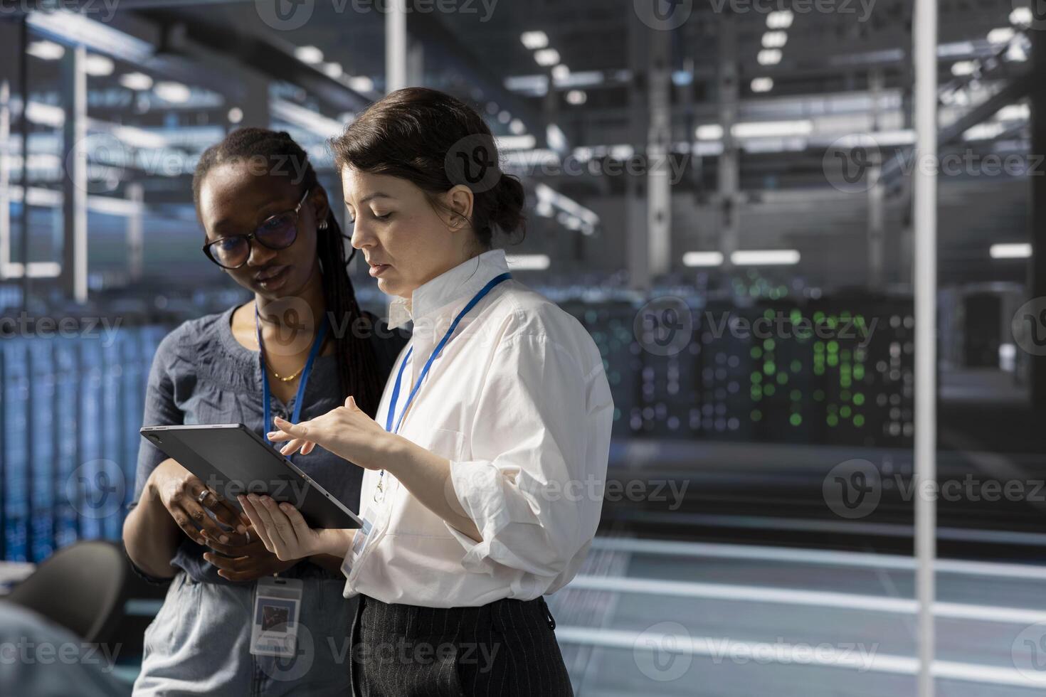 Engineers in data center using device, verifying firewall configurations. Teamworking IT professionals performing equipment vulnerability scans in server hub using tablet photo