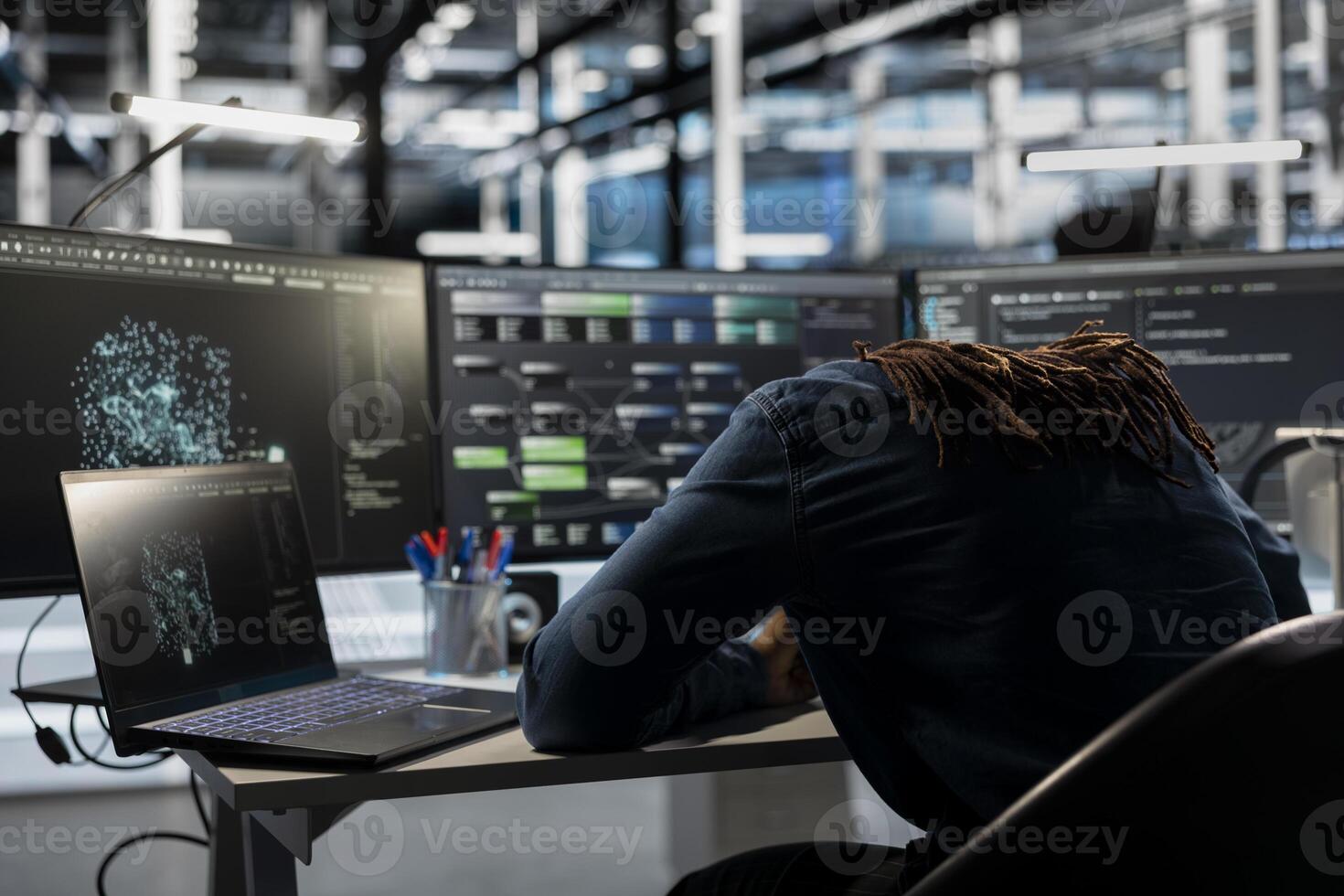 Exhausted server farm engineer falls asleep while looking at data analysis graph to reduce equipment failure. Tired data center worker exhausted after looking at AI visualization dashboard all day photo