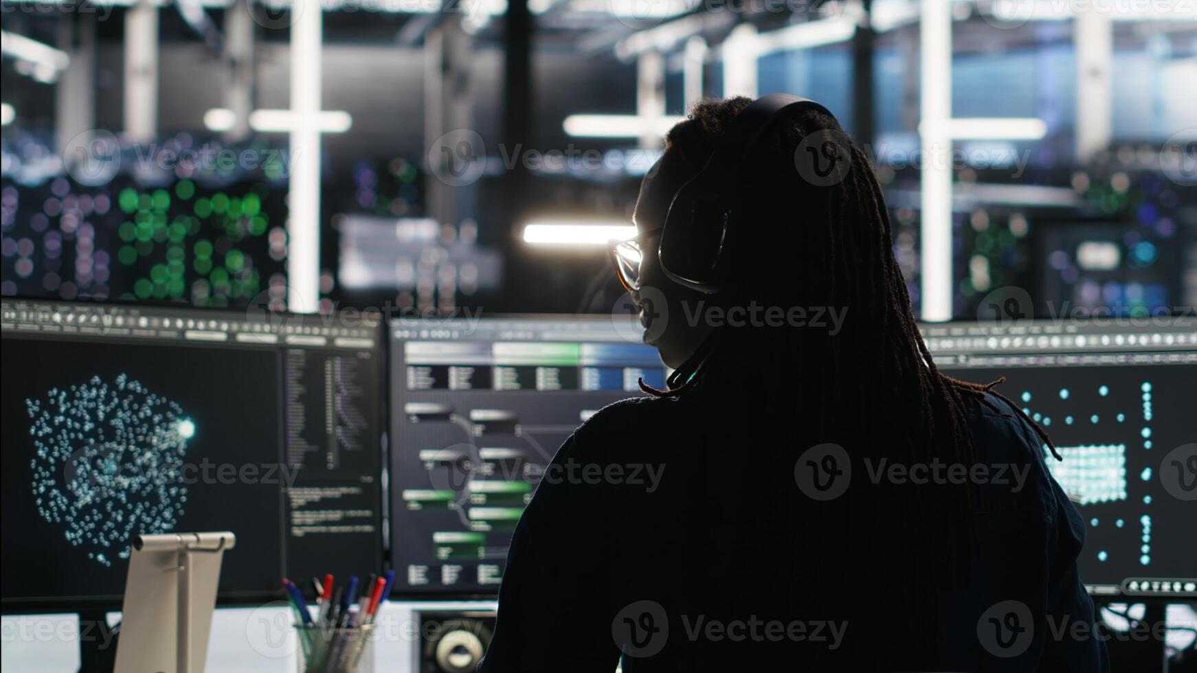Server room programmer interpreting data analytics graphs, putting on headphones. Data center IT expert uses artificial intelligence tool showing system metrics, listening music, camera B photo