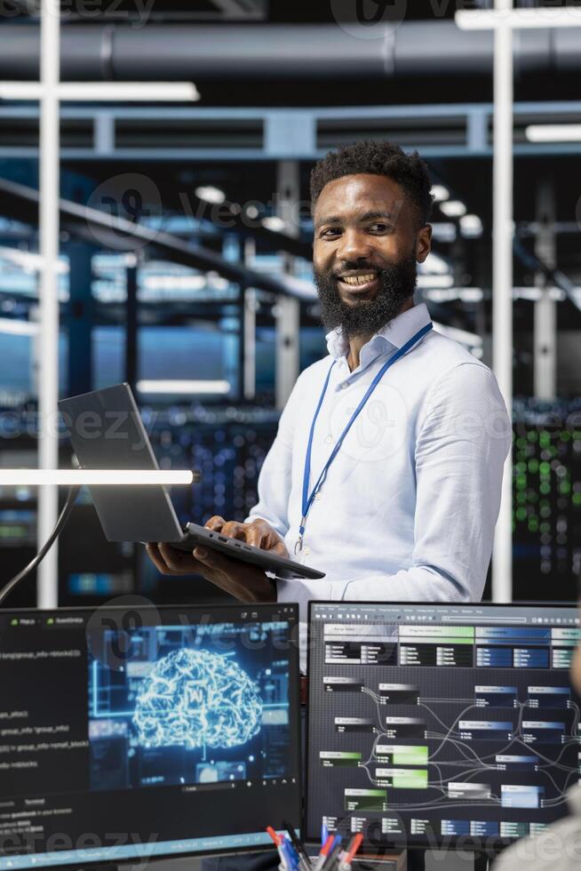 Cheerful man in server hub facility using artificial intelligence to perform demanding computing tasks. Jolly admin in data center uses AI technology for machine learning workloads photo