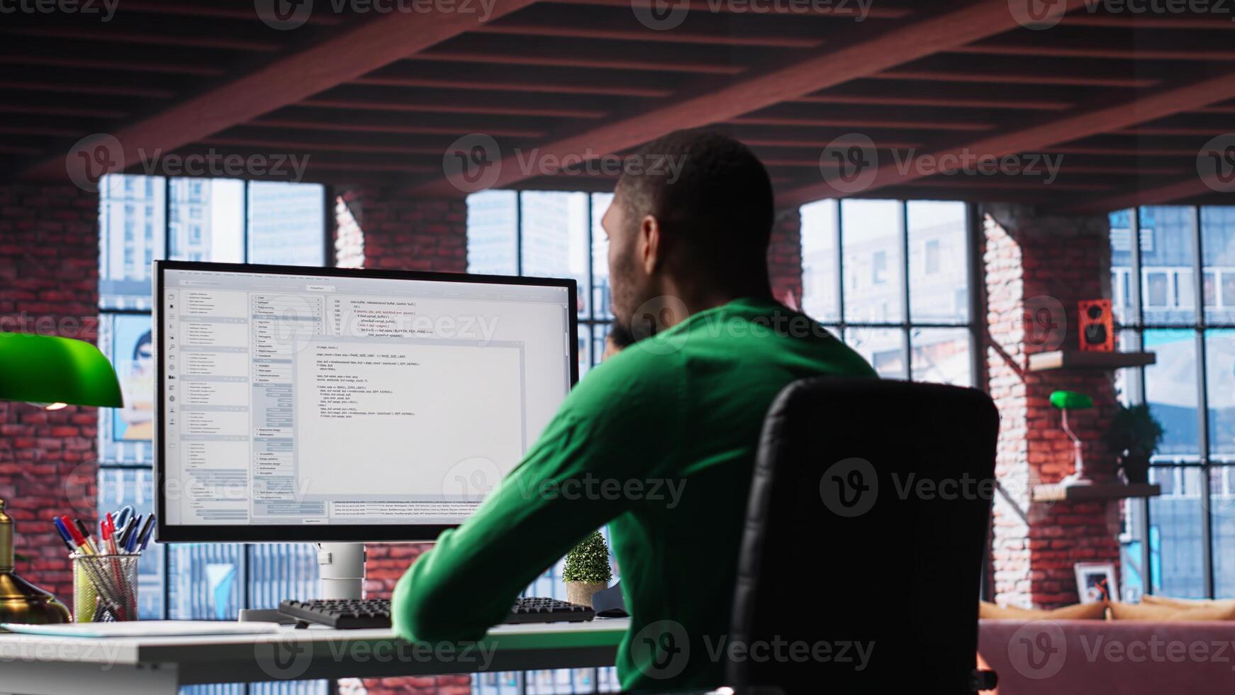 Black IT developer at PC coding and creating app software, implementing algorithms to fix errors. Engineer in loft working with code language, optimizing app performance. Camera B. photo