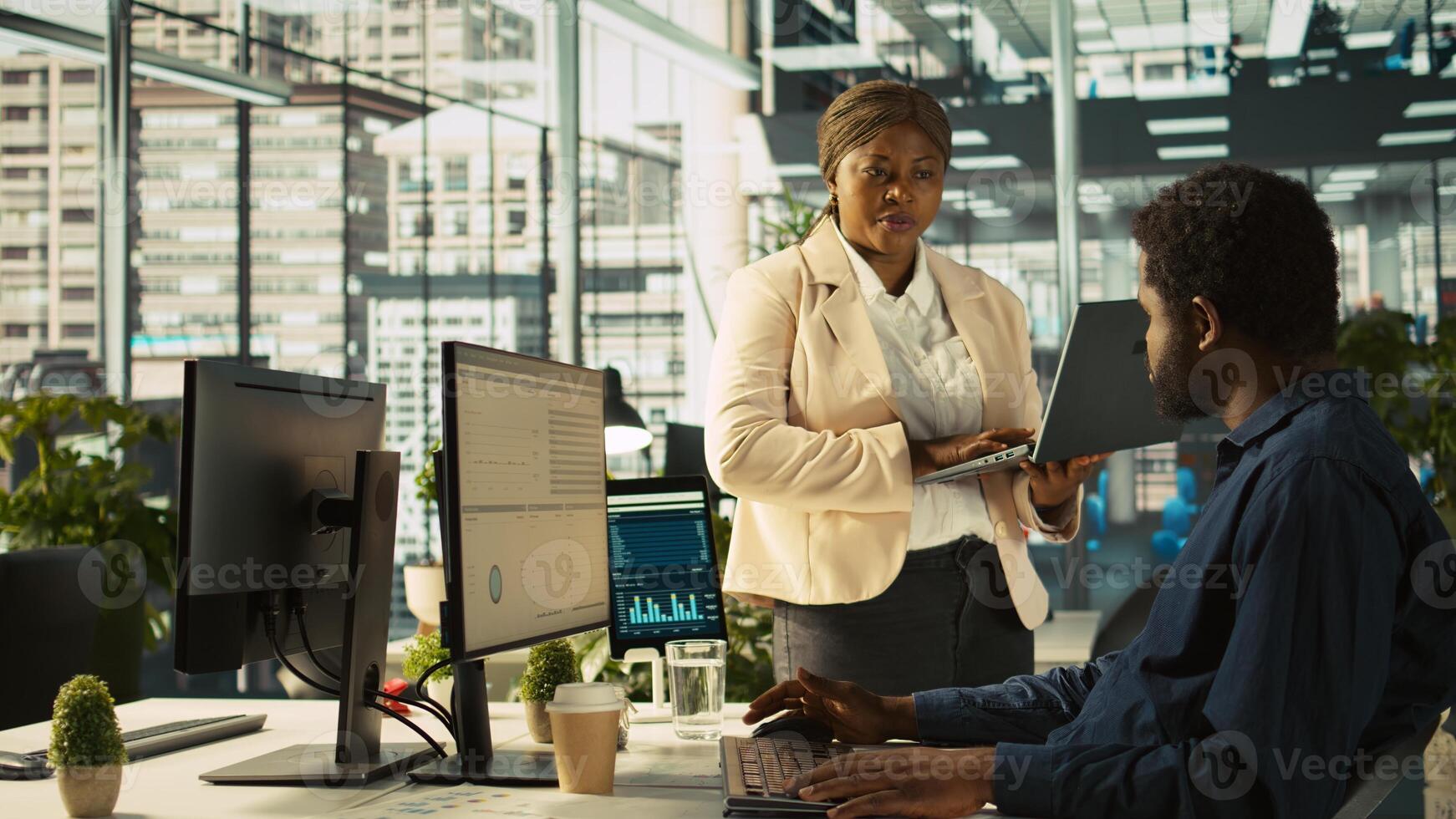 Manager in office ensuring worker hits key performance targets for revenue, profitability and operational efficiency. Corporate executive board member talks with employee, camera B photo