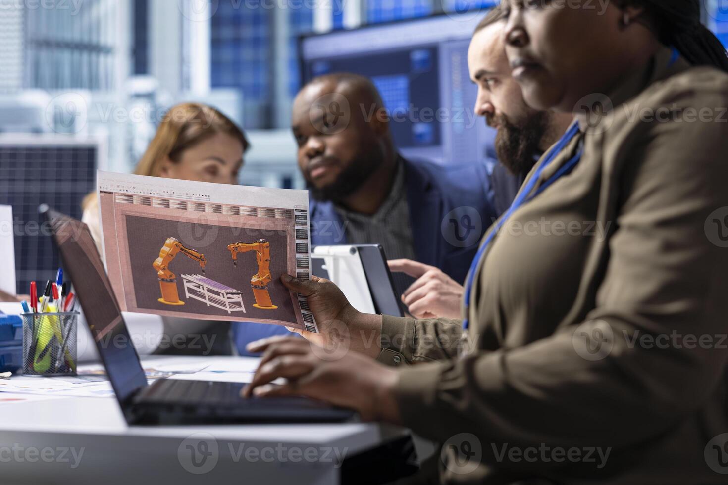 Photovoltaics factory managers look over schematics, planning work on facility machines using laptop. Solar panels plant shareholders look over assembly lines blueprints, working on notebook photo