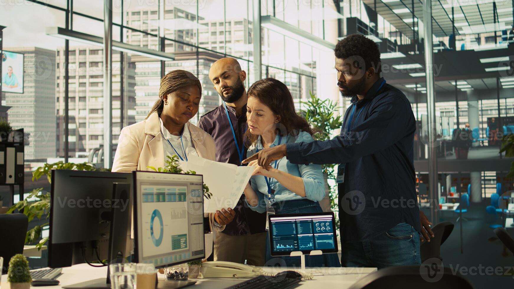 Smiling coworkers looking over revenue figures on paperwork in office. Happy team of accountants focused on comparing company statistical numbers to finish job before deadline, camera B photo