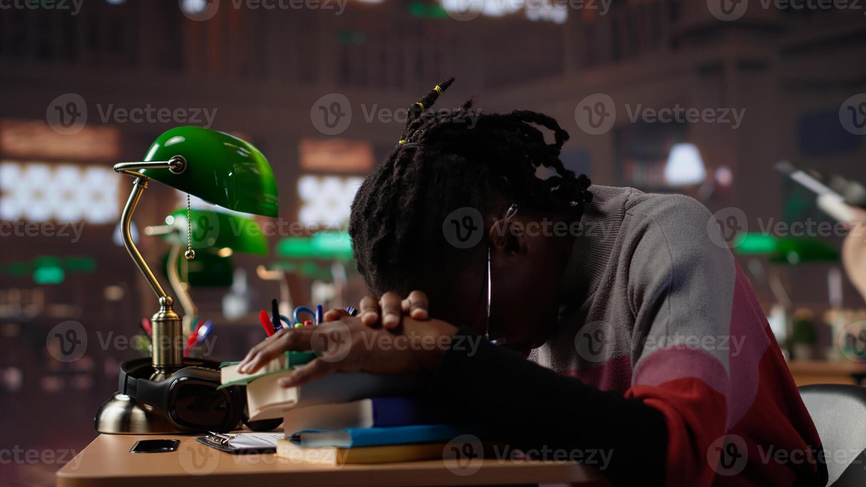 Female pupil struggling to stay focused and awake while researching, writing on bachelor paper at library in order to obtain university diploma. Complete studies. Camera A. photo