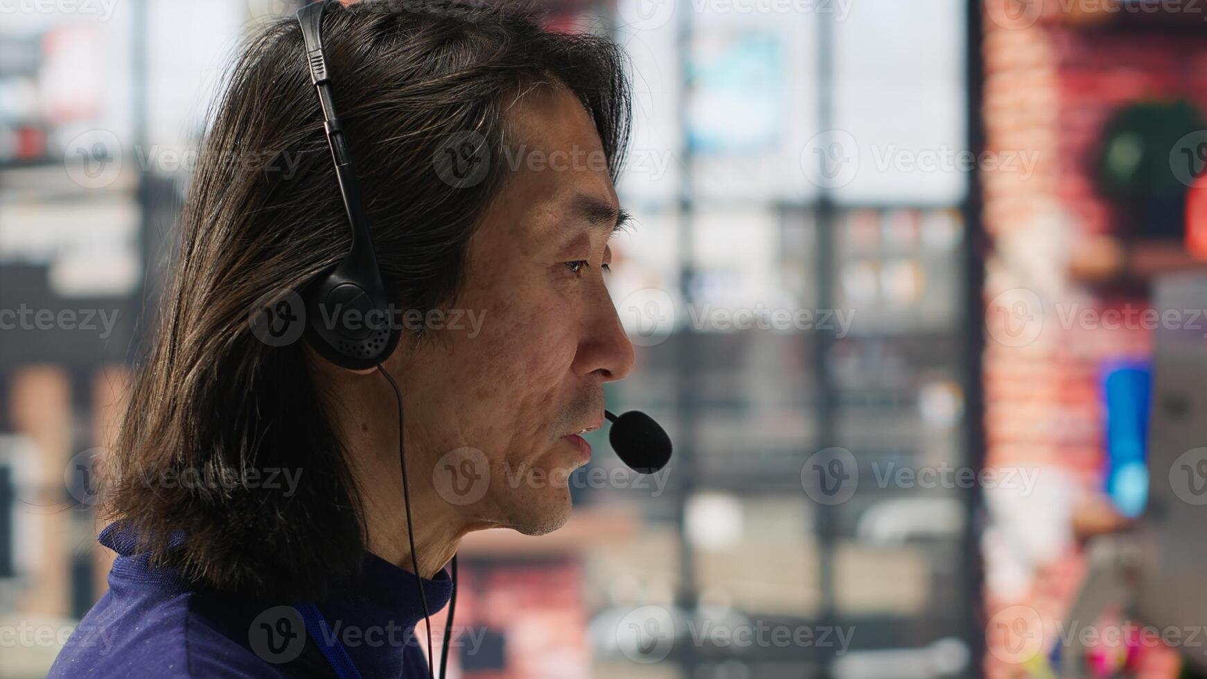 Closeup of call center agent helping customers regain access to accounts, resetting passwords. Experienced Asian worker in diverse customer center assisting clients needing help, camera A photo
