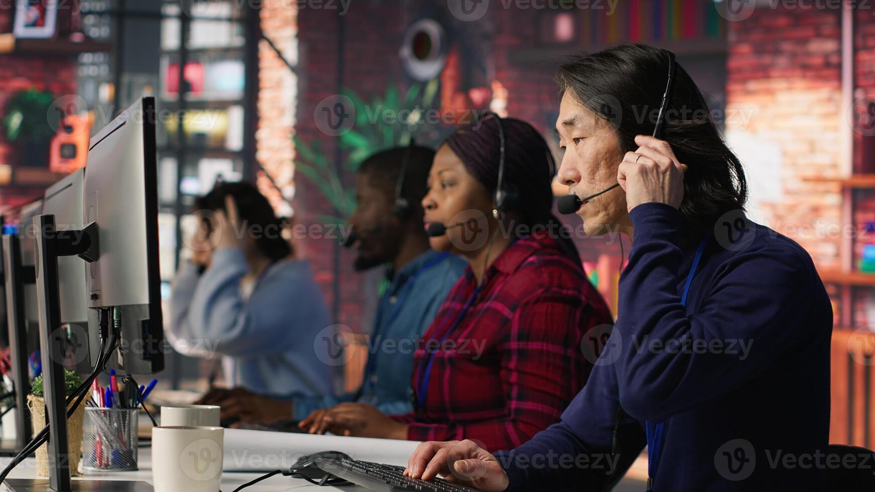 Call center employee listening to client inquiries and complaints. Asian senior customer service representative assisting customers with issues related to products or services, camera A photo