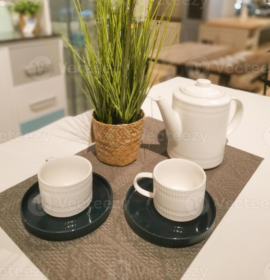 Composition with tea set and rattan vase on the white table. Preparation for a tea party with friends or relatives. Afternoon tea time. photo