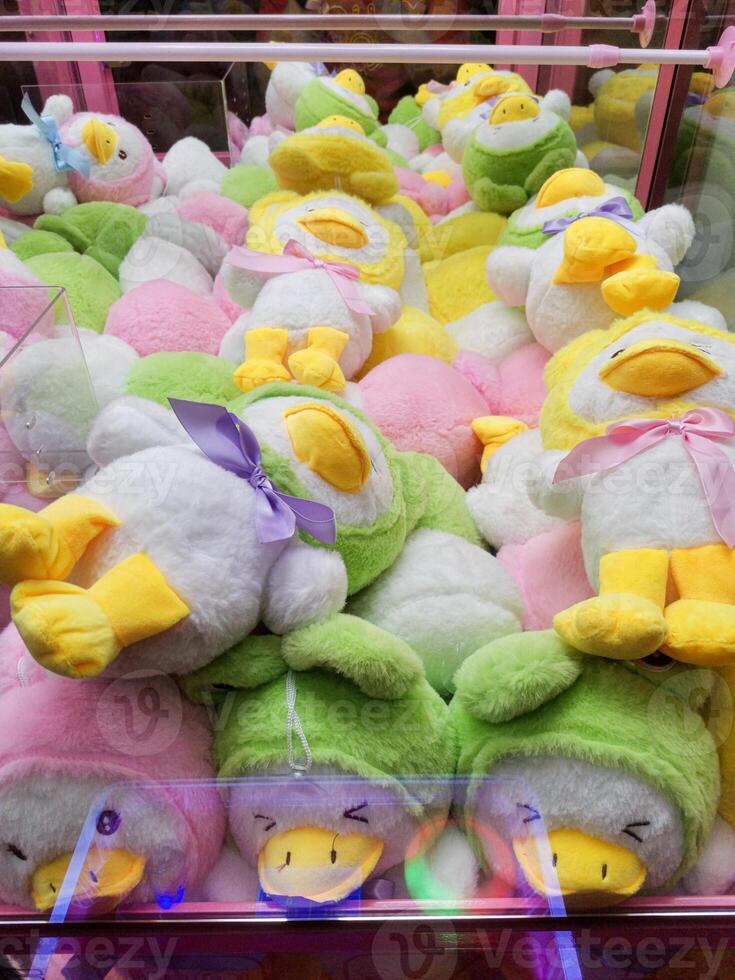 Duck plushies in an arcade claw machine. Vibrant, toys, excitement, plush, fun, carnival. photo