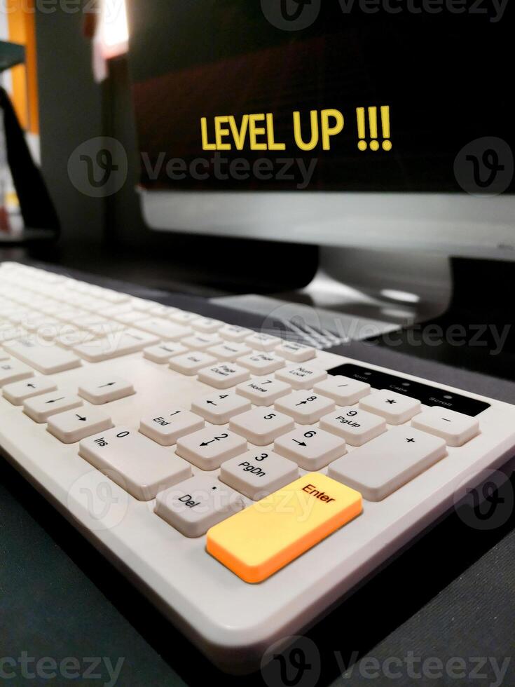 Computer monitor with Level Up written on it and keyboard. Enter key is yellow to indicate the action to be taken. Motivation, self-development and education concept. photo