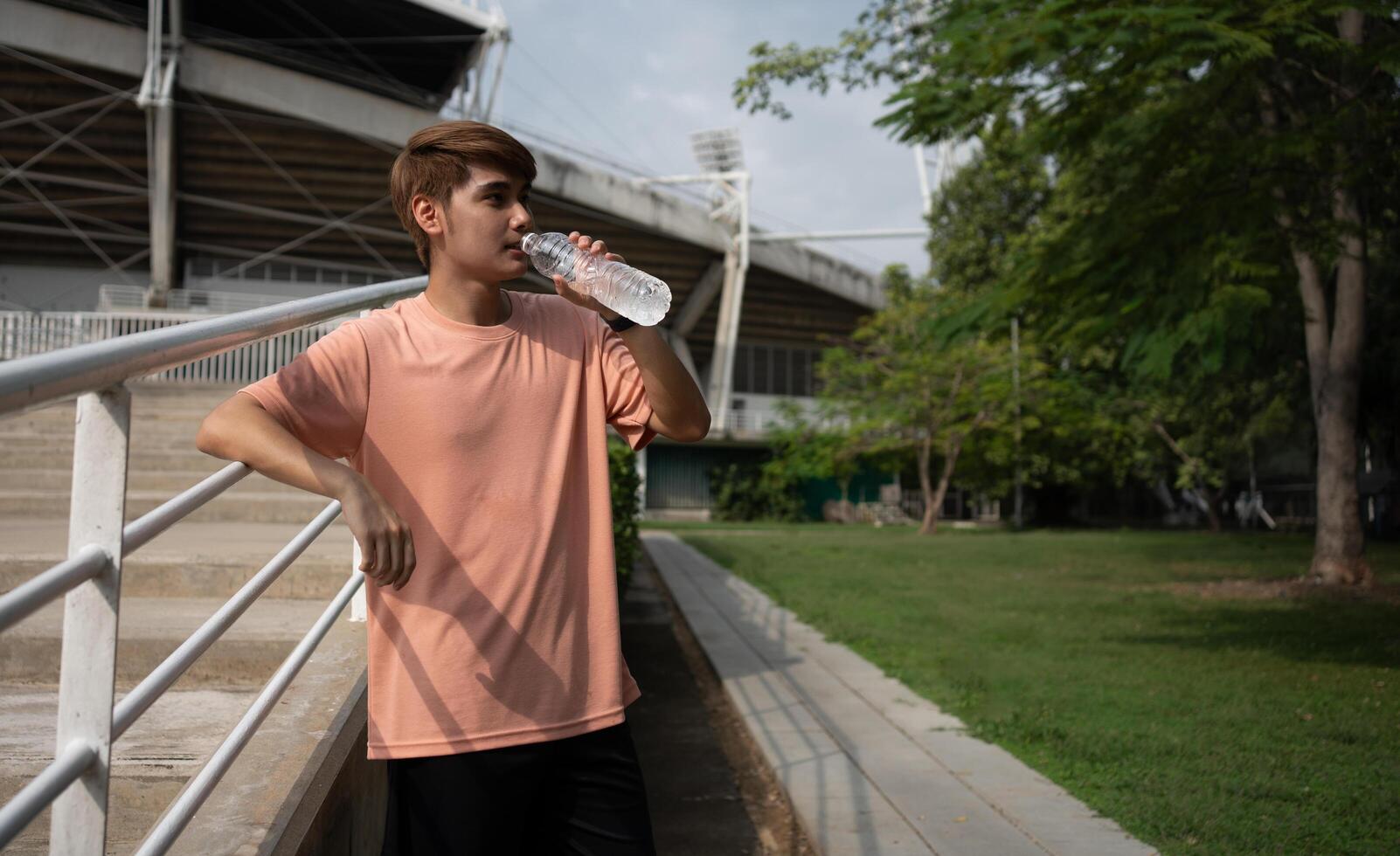 Happy healthy men drinking water from bottle after workout exercise. Sports, nutrition bottle, and men athletes drink liquid for hydration after exercising, a Healthy and active lifestyle concept. photo