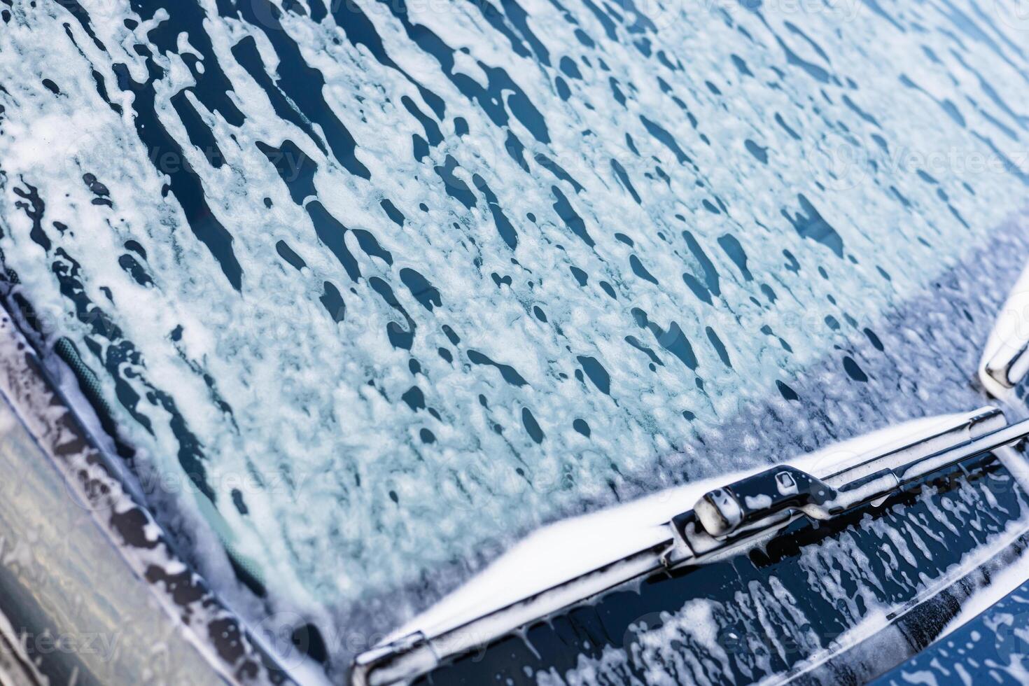 Washing car with soap on a sunny day in a driveway near the home photo
