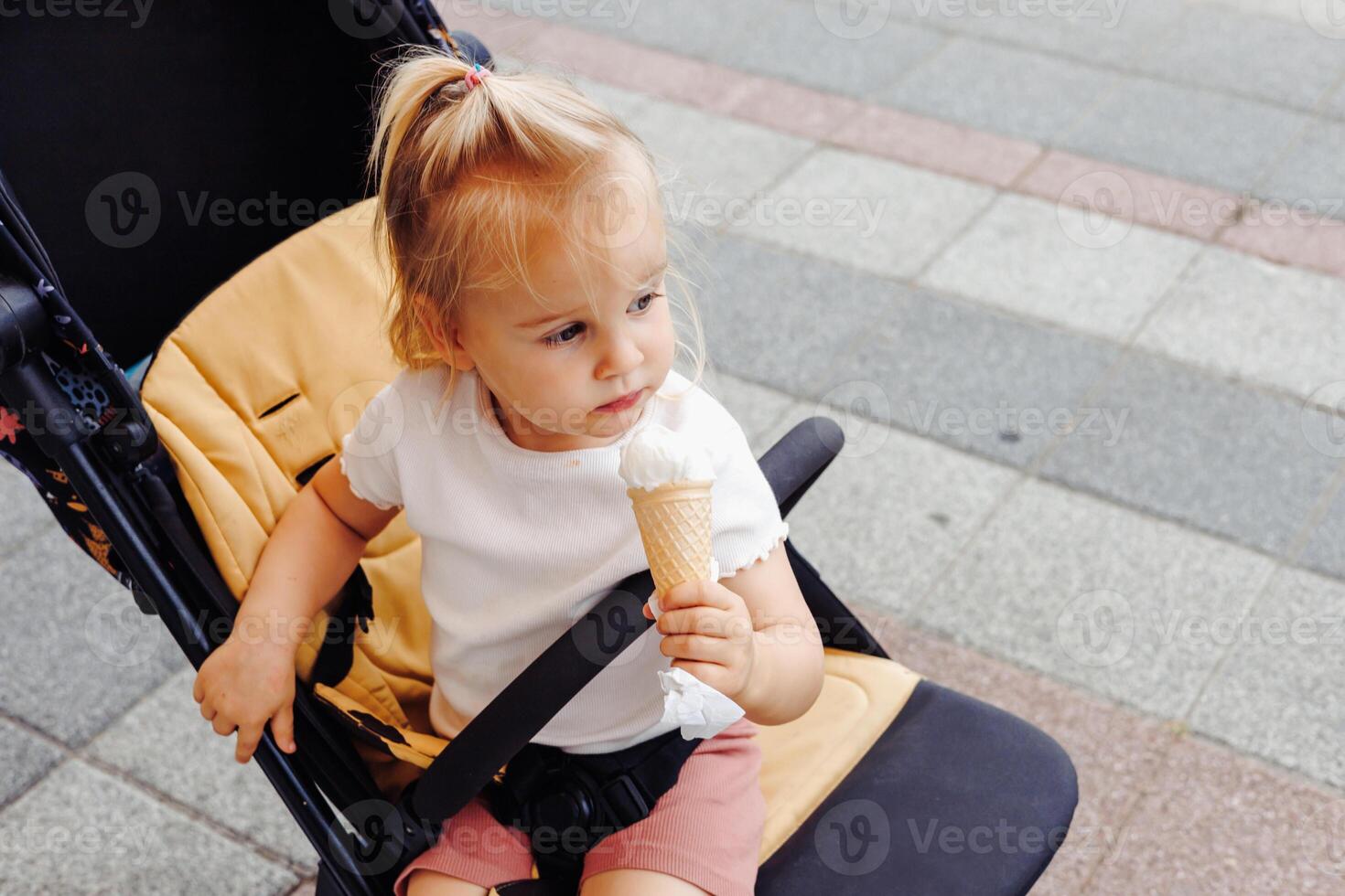Toddler girl enjoys ice cream while exploring the marina during summer trip with family. photo