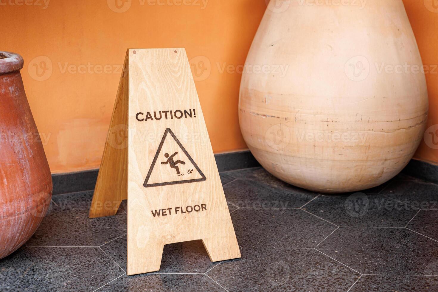 TheCaution sign warns about wet floor in indoor area near large pottery photo