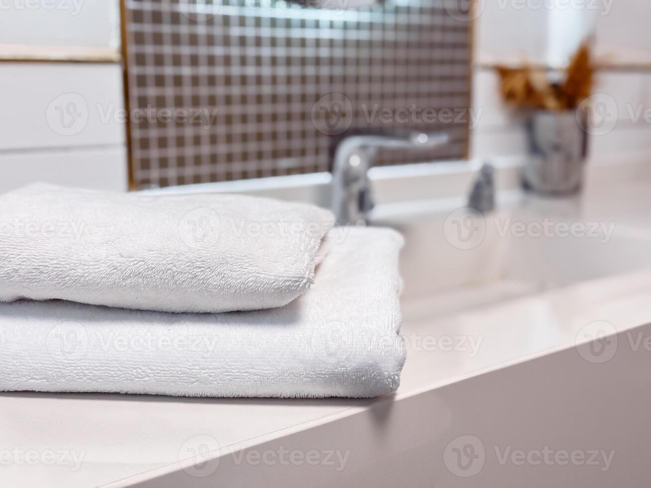 Soft white towels neatly stacked on a clean countertop in modern bathroom setting photo