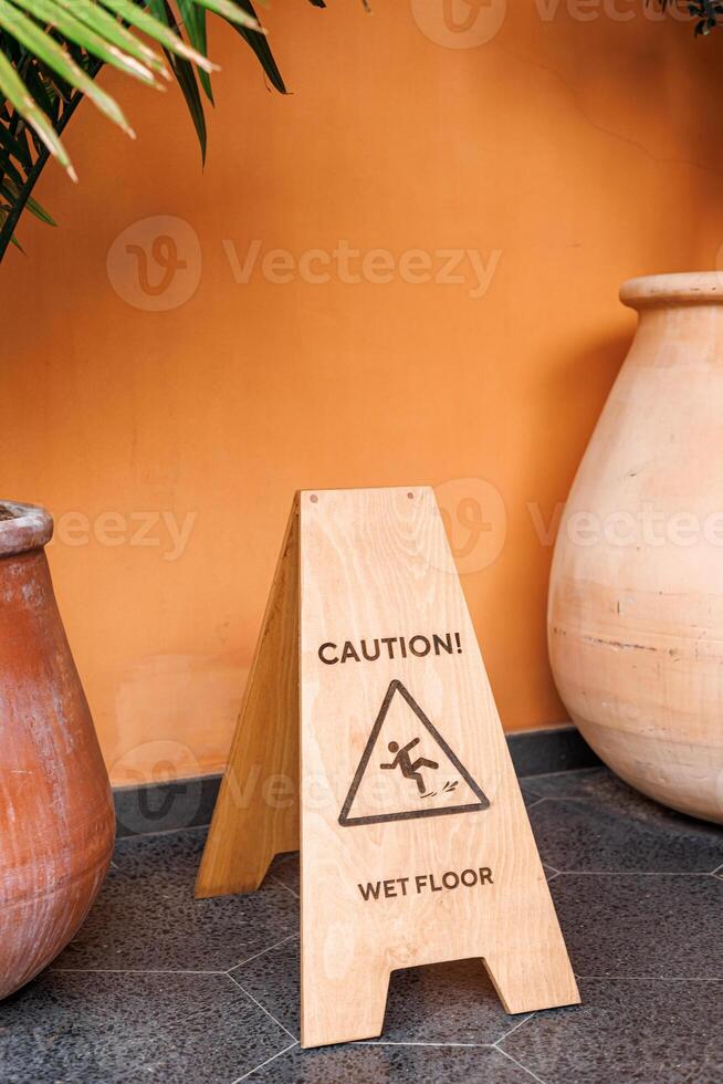 Caution sign warns about wet floor in indoor area near large pottery. photo