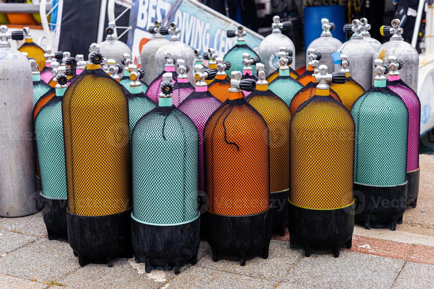 Colorful scuba diving tanks lined up at a dive shop in a coastal location during daytime photo